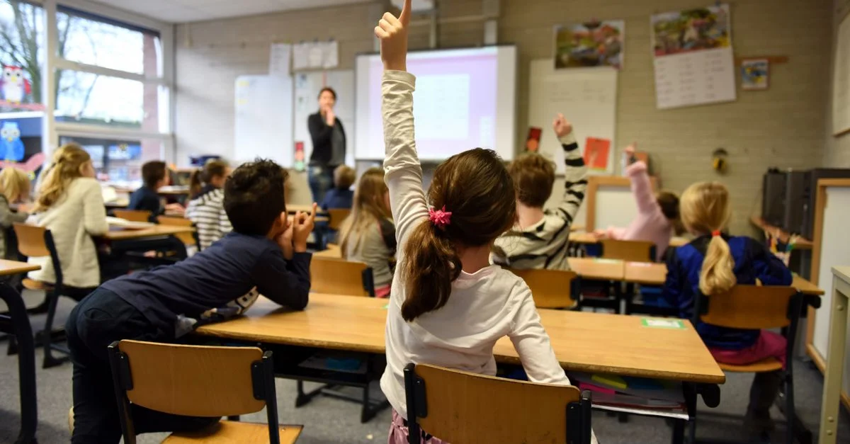 Scène de classe vivante avec des étudiants participant activement, levant la main pour un cours.