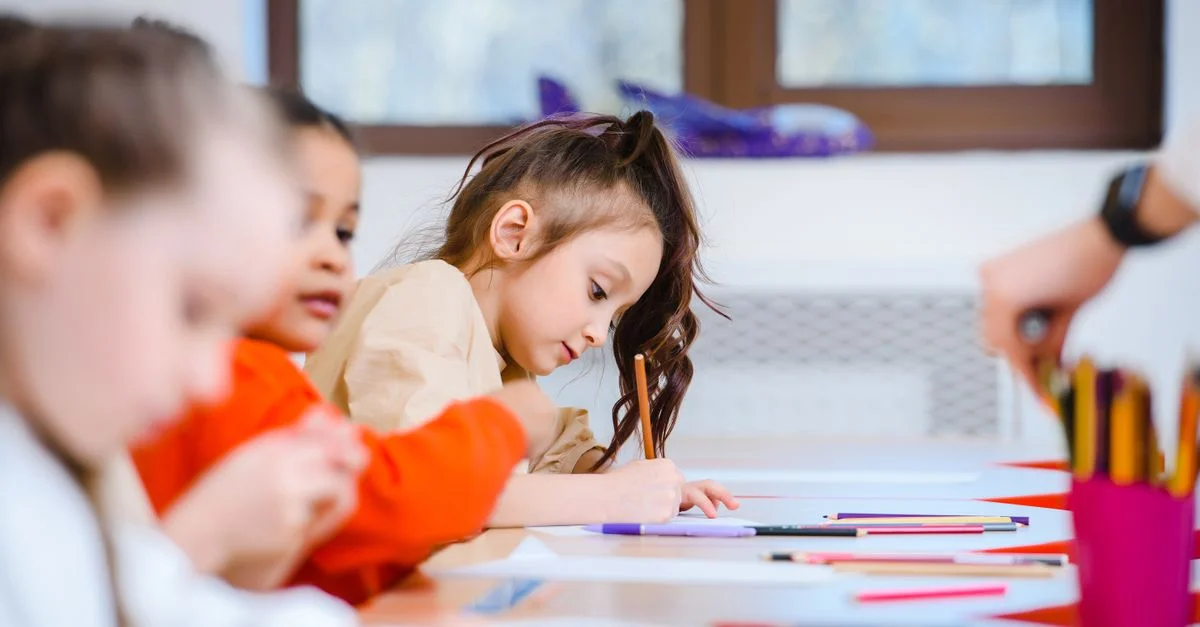 Des enfants engagés créativement dans un cours d'art, dessinant et coloriant avec des feutres vibrants.