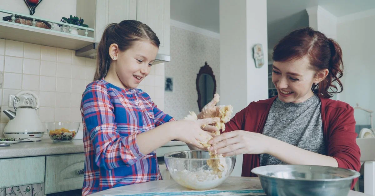 Une mère et sa fille s'amusent à cuisiner ensemble, en mélangeant de la pâte dans la cuisine.